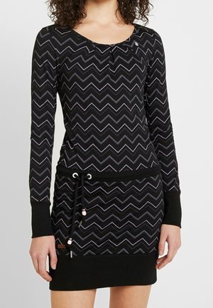 Musta mekko, jossa pitkät hihat ja violetti-valkoinen siksak-kuvio. Kuminauhavyötärö, jossa vaaleanpunaiset korostukset, ja pyöreä pääntie.