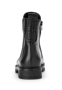Bottines en cuir noir avec une fermeture éclair sur le côté, tirette décorative cousue avec des perforations et semelle robuste, vues de l'arrière.