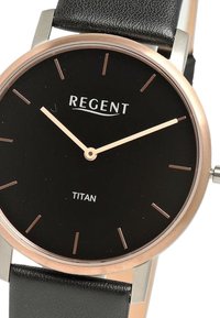 Montre noire au design minimaliste. Boîtier rond en métal rose doré, cadran noir, index des heures simples et bracelet en cuir noir. Inscription "REGENT TITAN."