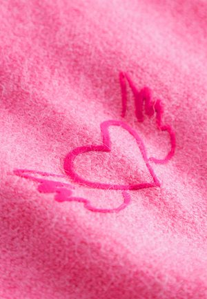 Roze viltstof met een geborduurd ontwerp van een hart en een vleugel. De stiksel is een iets donkerdere roze, wat de textuur versterkt.