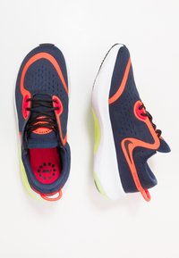 Běžecké boty Nike v tmavě modré síťovině s jasně oranžovými akcenty. Mají zaoblenou bílou podrážku se světle zeleným detailem. Černé tkaničky a vnitřní podšívka.