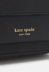 Czarny skórzany portfel z teksturowaną powierzchnią. Złote tłoczone logo marki "kate spade NEW YORK" z przodu. Subtelny detal w postaci przeszycia.