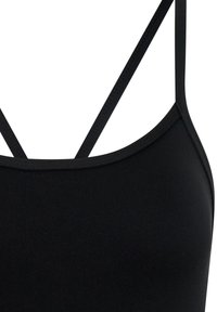 Soutien-gorge de sport noir avec de fines bretelles réglables, design sans coutures, texture douce et encolure ronde. Le matériau semble extensible et lisse.