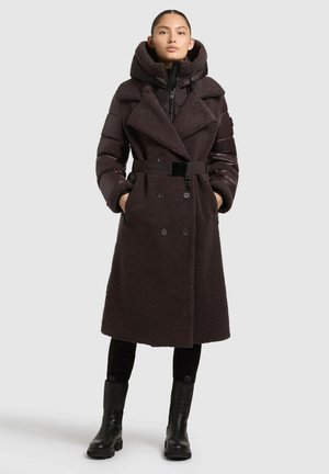 Mörkbrun dubbelknäppt kappa med en plyschliknande textur, stor krage, uppblåsbara ärmar och bälte. Stylicerat med svarta åtsittande byxor och stövlar.