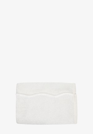 Serviette de bain blanche pliée avec un motif ondulé subtil près du bord sur un fond blanc uni.