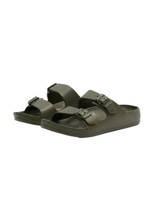 Sandalias de deslizar de color verde oscuro hechas de goma texturizada. Presentan dos correas ajustables con hebillas y una suela acolchada con un patrón de dibujo.