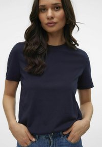 Mörkblå t-shirt med kort ärm, gjord av mjukt bomull, med rund hals och avslappnad passform, tillsammans med denimjeans.