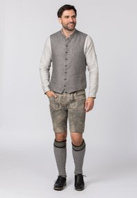 Grau leinener Weste mit Knopfleiste, beige Langarmhemd, graue Lederhosen mit gestickten Details und knielange graue Socken mit schwarzen Akzenten.