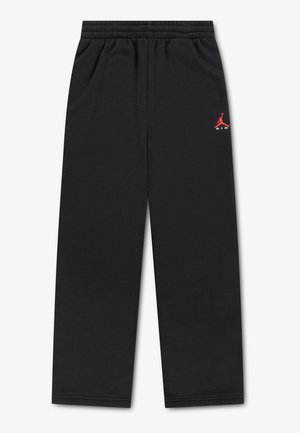 Pantalon de jogging noir à taille élastique avec un petit logo Jumpman Air Jordan rouge sur la cuisse gauche, posé à plat sur un fond blanc.