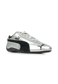 Zapatillas deportivas plateadas y negras con un diseño elegante, suela de goma y detalles de ante texturizado; presenta el logo de PUMA en el lateral y la lengüeta.