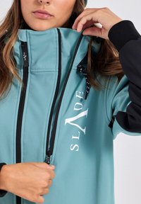 A teal jacket with black accents, featuring a high collar, zippered front, adjustable drawstring, and large white logo.