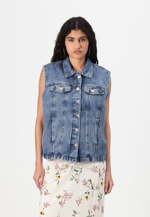 Chaleco de denim en azul claro, diseño sin mangas, con un cuello puntiagudo, cierre frontal de botones y dos bolsillos en el pecho. Tejido texturizado.