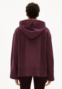 Felpa oversize con cappuccio in viola scuro, caratterizzata da una vestibilità ampia e maniche lunghe. Tessuto liscio con orlo a coste.