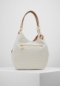 Sac à main crème avec motif logo MK beige, poignée en cuir marron, poche zippée dorée et pendentif MK doré suspendu à la poignée.