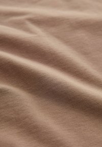 Tessuto di cotone in una sfumatura taupe tenue, con una fine trama a righe, morbido al tatto e con un leggero luccichio. Ideale per capi estivi.