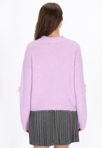 Lavendelfarbener Strickpullover mit geripptem Ausschnitt, ausgestattet mit einem grauen, plissierten Saum und dekorativen Akzenten an den Ärmeln. Weiches, strukturiertes Material.
