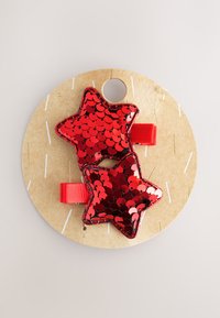 Red sequin hair clips in star shapes, attached to a round cardboard display. Features vibrant color, glossy texture, and smooth edges.