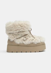 Botte d'hiver beige avec semelle épaisse en caoutchouc, doublure et bordure en fausse fourrure douce, et détail de lacets autour de la cheville et à l'avant.