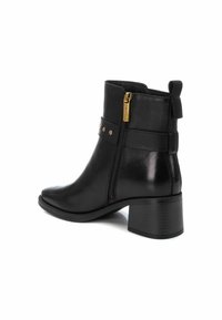 Botín de cuero negro hasta el tobillo con punta redonda, cremallera lateral, herrajes dorados, tachuelas decorativas y un tacón de bloque texturizado.