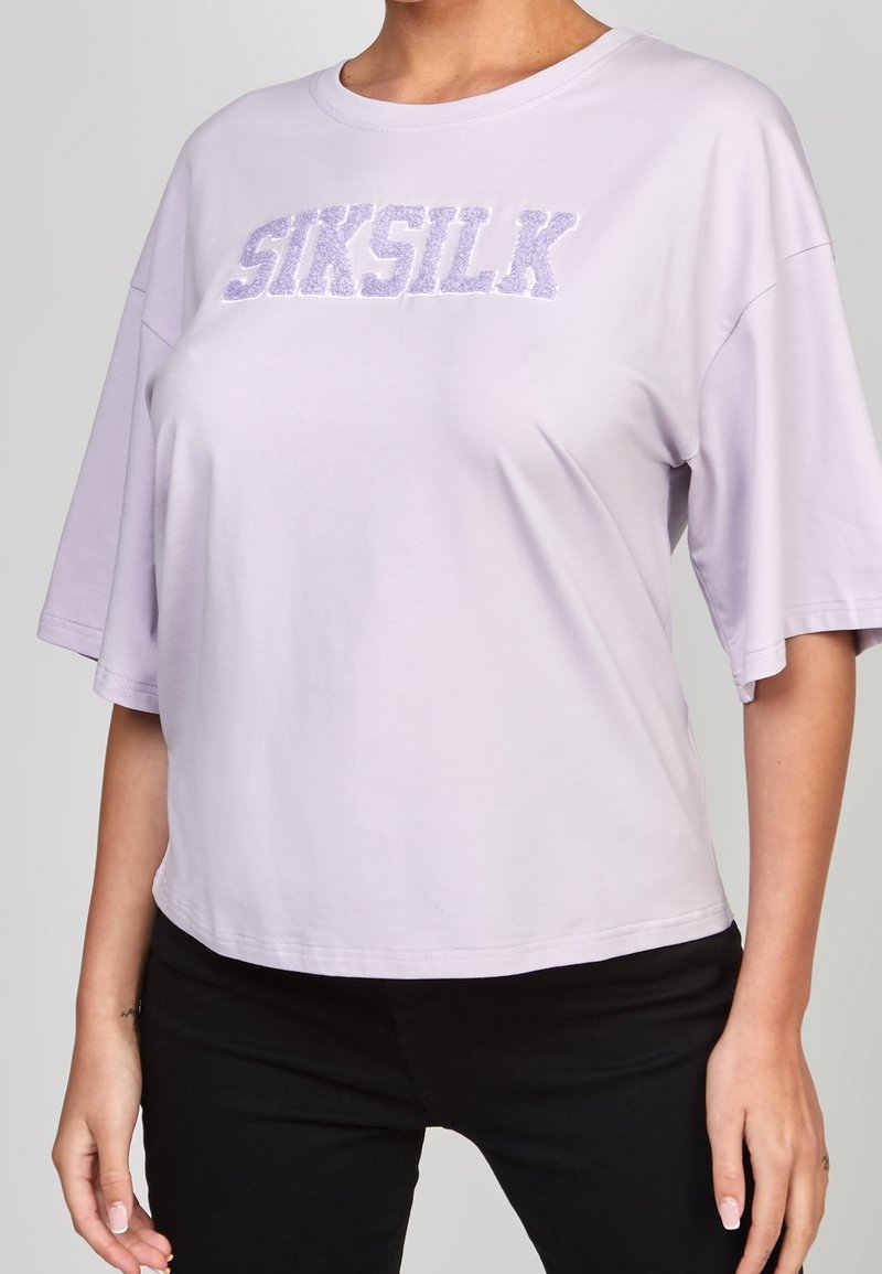Ljuslila t-shirt med korta ärmar och lös passform, rundad halsringning, med texturerad "SIKSILK"-text i mörkare lila.