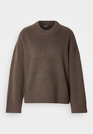 Καφέ πλεκτό πουλόβερ με στρογγυλή λαιμόκοψη, μακριά μανίκια και ριμπ τελειώματα στα μανίκια και στο τελείωμα, απλωμένο σε λευκό φόντο.