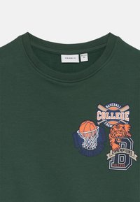 Felpa verde con collo rotondo, caratterizzata da stampe grafiche di un canestro da basket, una tigre e il testo "COLLEGE" in colori contrastanti.