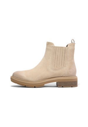 Beige ruskind Chelsea-støvle med elastisk sidepanel, trækstrop, gummisål, lavt træhæl og prægede logo nær hælen.
