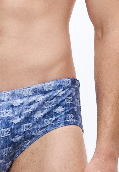 Bañador tipo slip con estampado de mezclilla en color azul claro, textura suave y una amplia cinturilla elástica con logotipos sutiles en la tela.