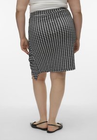 Sukňa vzoru houndstooth v čiernobielej, po kolená s bočným rozparkom a elastickým pásom, vyrobená z hladkej látky. Ploche čierne sandále.