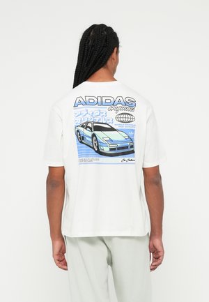 Pikkade punutistega mees kannab valget Adidas t-särki, millel on sinise sportauto graafika ja jaapani keeles tekst seljal.