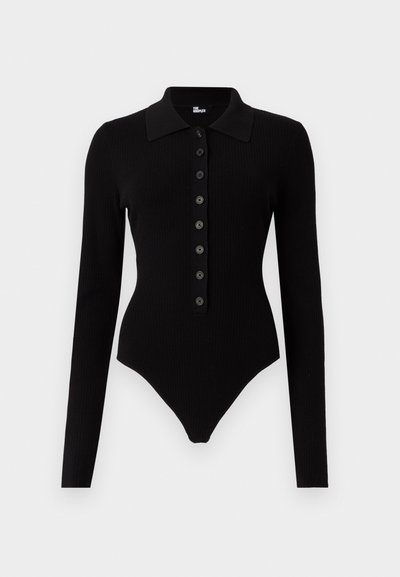 Μαύρο ριμπ κορμάκι με μακρύ μανίκι, με μυτερό γιακά και σειρά από οκτώ κουμπιά μπροστά, εφαρμοστή γραμμή με ψηλές ανοίγματα στα πόδια.