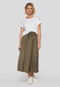 White short-sleeve shirt with small metallic accents paired with a long olive green skirt featuring an elastic waistband and drawstring. White sneakers.