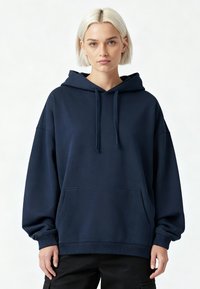 Mornarsko modra oversized kapuca iz mehkega blaga, z vrvico na kapuci, sprednjim žepom in rebrastimi manšeti. Gladka tekstura z minimalnim dizajnom.