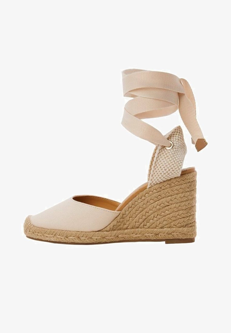 Chaussure compensée espadrille beige avec talon en jute tressé et lien à nouer à la cheville, bout fermé et panneau arrière texturé.
