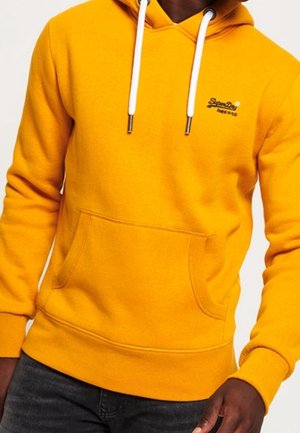 Sudadera amarilla con un bolsillo frontal, capucha con cordón y logo de "SuperDry". Hecha de una tela suave con puños y dobladillo acanalados.