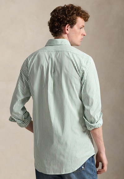 Striped shirt in green and white, featuring a classic collar, button-down design, and rolled sleeves. Cotton fabric with a smooth texture.