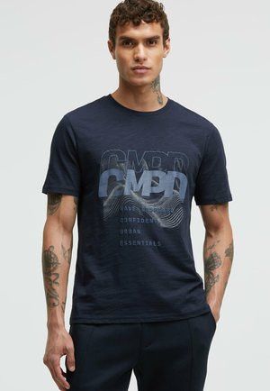 Navyblaue T-Shirt aus weichem Stoff, mit einem grafischen Druck, der das Wort "CMPD" und Wellenmuster zeigt. Kurze Ärmel und ein Rundhalsausschnitt.