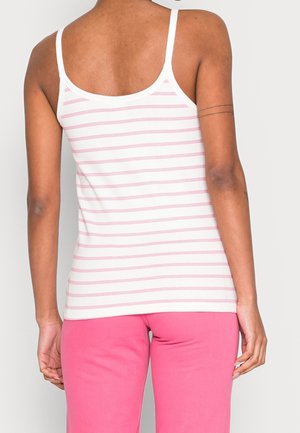 Un débardeur rayé en coton blanc et rose clair ; il présente des bretelles fines et une texture côtelée, associé à un pantalon rose uni.