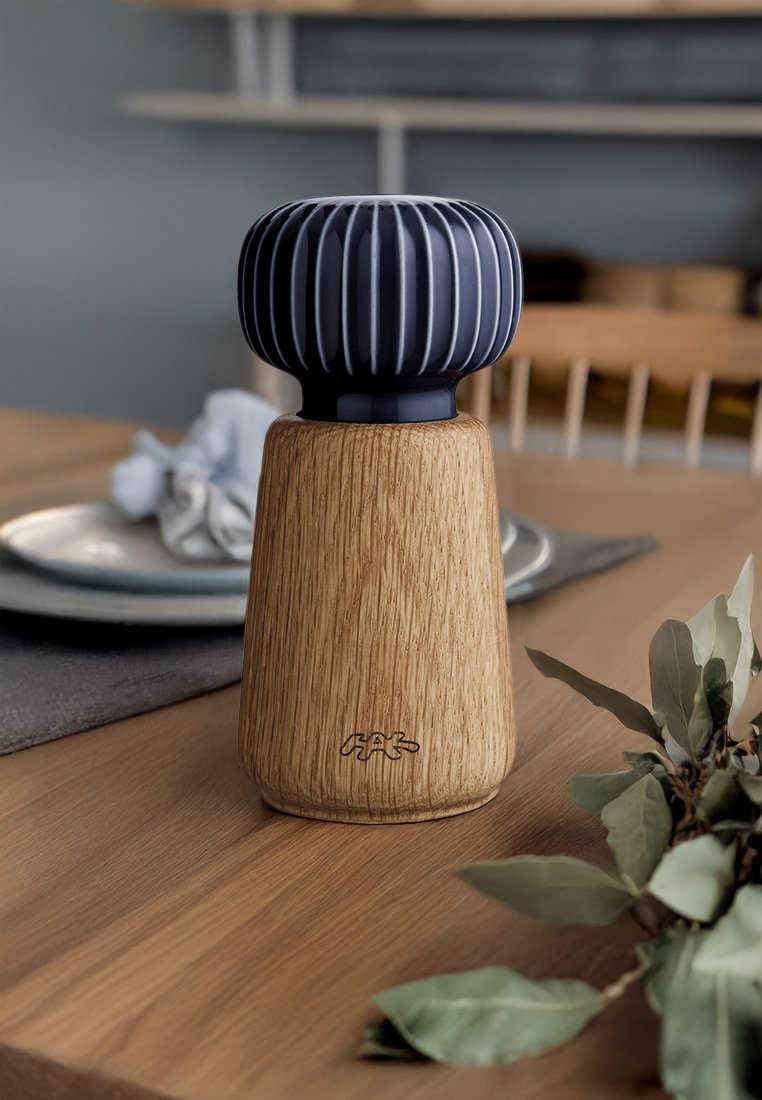 Ceramiczny wazon z granatową, prążkowaną górną częścią i zwężającą się jasną drewnianą podstawą. Posiada naturalną teksturę oraz subtelne logo na podstawie.