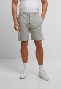 Grijze katoenen shorts met een elastische tailleband en trekkoord, voorzien van zijzakken en een klein zwart logo op de voorkant.