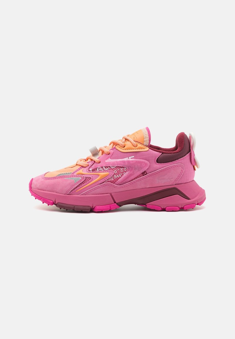 Chaussure de sport rose présentant un mélange de matériaux, y compris du daim et du mesh. Les détails notables incluent des accents orange contrastants et une semelle texturée.