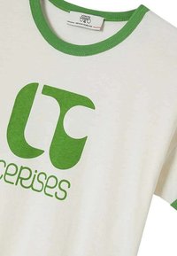 T-shirt en coton blanc avec col et manches côtelés verts contrastés. Il présente un grand texte stylisé en vert qui dit "exercices".