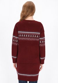 Bordó kötött pulóver geometrikus fair isle mintával fehér, tengerészkék és fekete színekben a vállrészén és az ujjain. Hosszú, bő szabású.