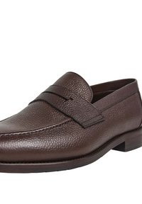 Mocasín de piel texturizada marrón con tacón bajo y detalle de tiras en la parte superior, mostrado en un ángulo de tres cuartos sobre un fondo blanco.