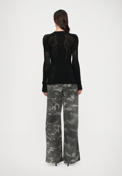 Haut à manches longues noir avec un design texturé et perforé, aux manches ajustées ; associé à un pantalon large gris à motif camouflé en tissu doux.