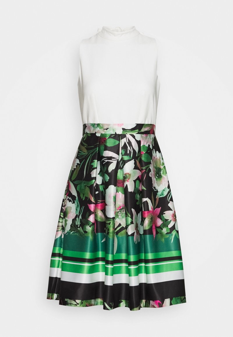 Robe top blanche sans manches avec un col haut et une jupe plissée avec des motifs floraux et rayés noirs, verts, blancs et roses.
