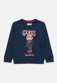Sweatshirt azul-marinho feito de algodão, apresentando uma gráfica de um urso com uma jaqueta, com o texto "GUESS" e "LOS ANGELES EST. 1981" impresso abaixo.