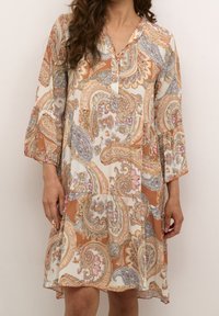 Sukienka w wzór paisley, utrzymana w naturalnej kolorystyce pomarańczowej, kremowej i niebieskiej, z zapięciem na guziki i rękawami o długości trzy czwarte z dzwonkiem.