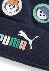 Námořnická pletená čepice s třemi kulatými nášivkami s kreslenými obličeji, plus výšivka loga "PUMA" v různých barvách a silueta bílého kotěte.