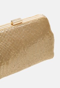 Zlatá síťová psaníčko s obdélníkovým tvarem, se hladkým kovovým uzávěrem a strukturovaným mřížkovým vzorem po celém povrchu.